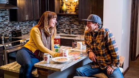 a couple sitting at a granite kitchen breakfast bar chatting over breakfast bowls