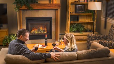a couple relaxes with wine by a cozy fireplace inside the fraser crossing founders pointe vacation rentals in winter park colorado