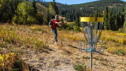 person playing at the mountain terrain winter park resort disc golf course in colorado