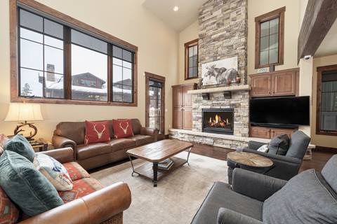 Living room with stone fireplace and three cozy couches arranged around. 