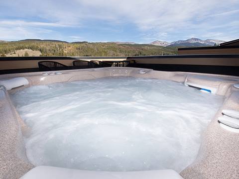 An outdoor hot tub with a mountain view in the background at an Arrow Townhome vacation rental at Winter Park Resort