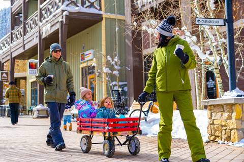 Family at Winter Park Resort in Colorado enjoying coffee and a walk with their children 