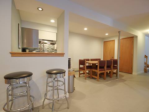 Finished basement with bar stools and dining table in the background. 