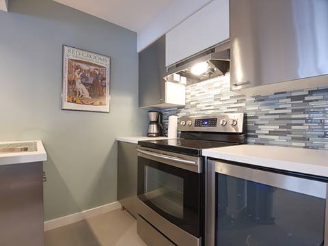 Basement kitchen with gray walls and a green tile backdrop. 