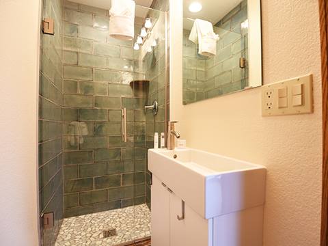 Bathroom with green tiling and sink in the foreground. 