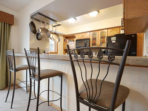Bar with bar stools and kitchen in the background. 