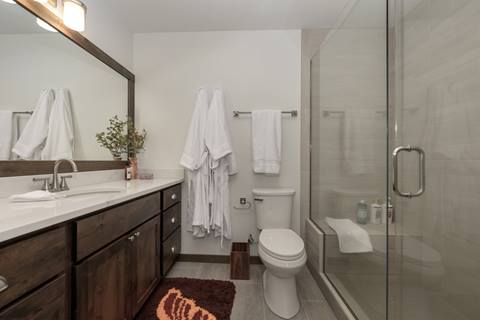 Modern bathroom with wide mirror, double robe hooks, and glass shower enclosure.