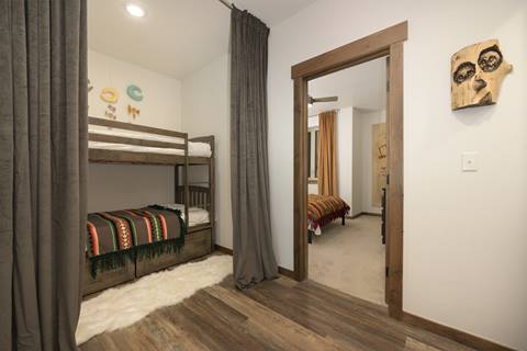 Bunk room with two twin beds, colorful striped blankets, and curtain divider.