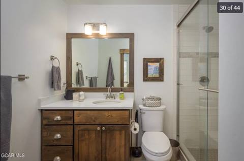 Bathroom with wood vanity, framed mirror, and glass shower enclosure.
