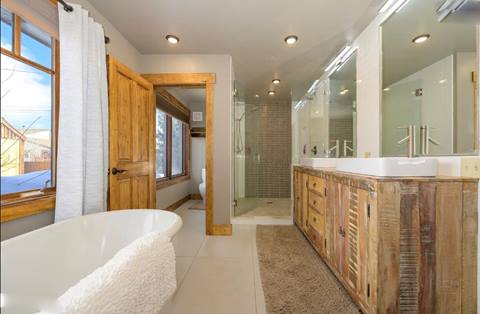 Bathroom with freestanding soaking tub, dual vanities, glass shower, and rustic wood accents.