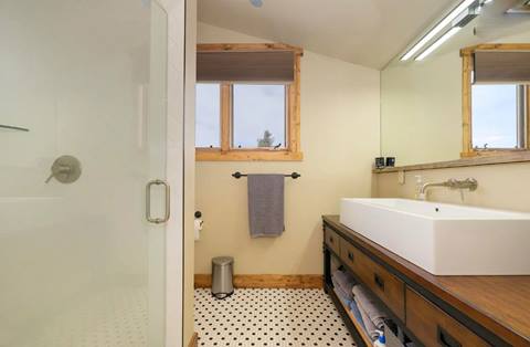 Bathroom with glass shower, large vanity with modern sink, and black-and-white tile floor.