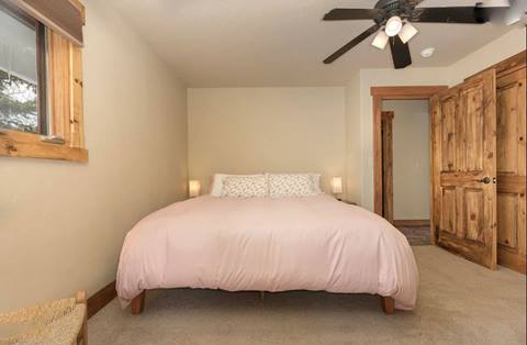 Bedroom with queen bed, pink bedding, and ceiling fan.