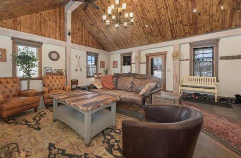 Opulent interior with red couch, gray couch, and leather chair. Chandelier hanging above them. 