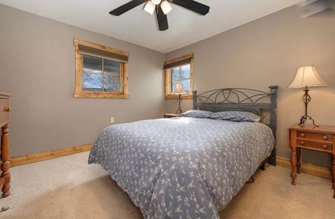 Bedroom with queen bed, dark blue bedding, neutral walls, and wood trim.