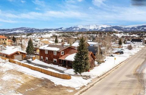 Aerial view of the home in winter, surrounded by snow with mountain views in the background.
