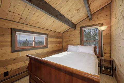 Queen bedroom with queen bed and white blanket over top. 
