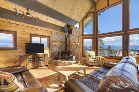 Living room with leather couches, large windows overlooking the mountains below. 