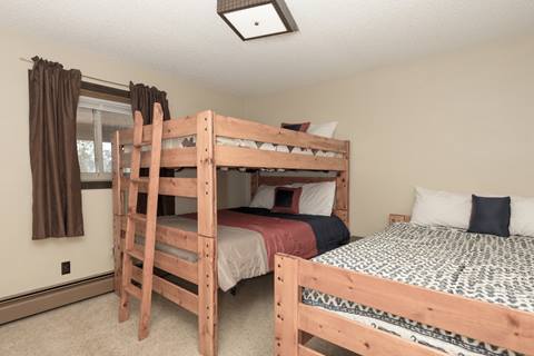 Bunk bed with wooden structure next to a queen bed with same wooden structure. 