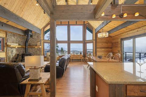 Large dining are with living room to the left and large picture window in the background. 