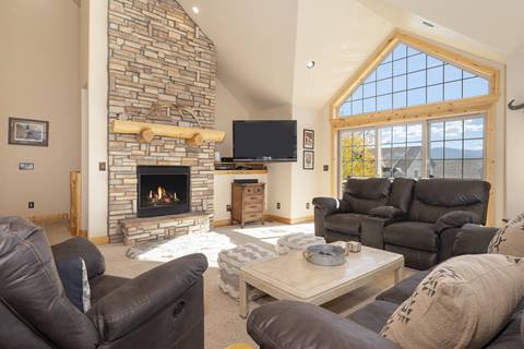 Spacious living room with two chairs and a large picture window with a wooden frame. 