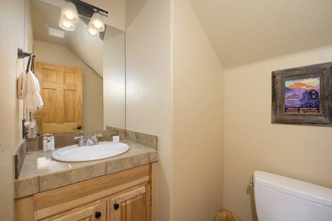 Half bathroom with mirror, sink, and framed Rocky Mountain artwork.