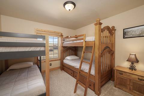 Bunk room with two sets of bunk beds and a wooden dresser.