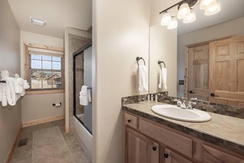 Bathroom with single sink, wide mirror, and combined shower/tub with tile surround.