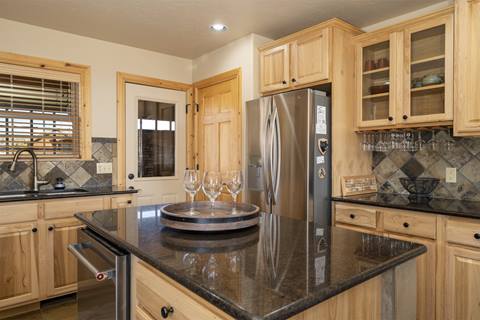 Kitchen with stainless steel refrigerator, granite counters, and wood cabinetry.