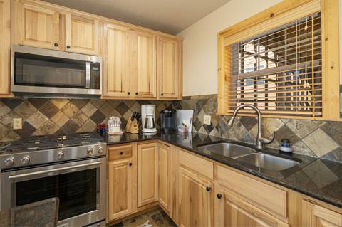 Kitchen corner view with gas stove, microwave, and tile backsplash.