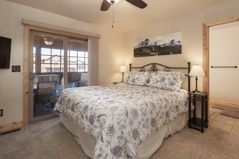 Bedroom with king bed, patterned bedding, sliding glass door to deck, and attached bathroom.
