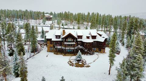 Large mountain home surrounded by evergreens taken during winter with a snow-covered ground. 