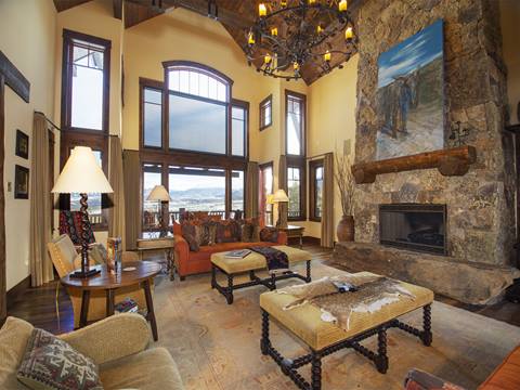 Large living room with decadent wall decorations, lavish furniture, and a large stone fireplace. 