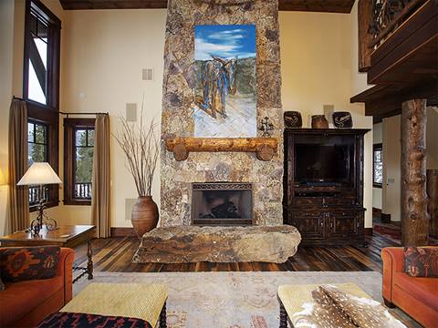 Living room with stone fireplace and a painting hung at the center.
