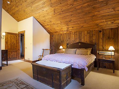 King bedroom with slanted ceilings and white bed clothing. 