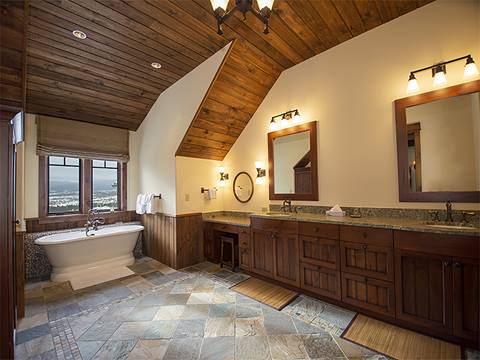 Stone-floored bathroom with slanted wooden ceilings. 