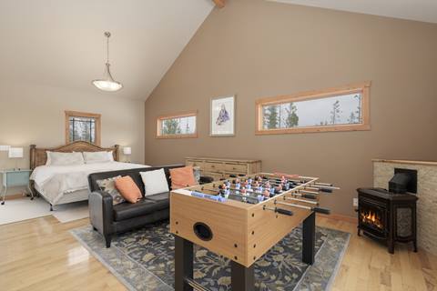 Bedroom with king bed, high ceiling, foosball table, and gas stove with flame.