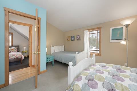 Bedroom with two twin beds, bright turquoise walls, and large window providing natural light.