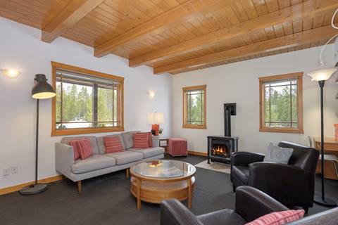 Cozy living room featuring gray sofa, leather chairs, glass coffee table, and corner wood-burning stove.
