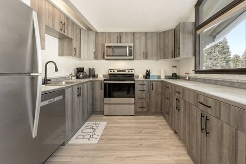 Modern kitchen with stainless steel appliances, gray cabinetry, and wide counters.