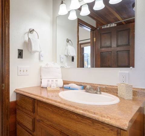 Bathroom vanity with sink, wood cabinetry, and bright mirror lighting.
