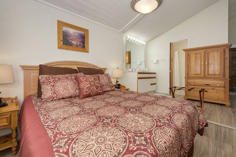 Bedroom with patterned red bedding, wood furniture, and ensuite vanity.