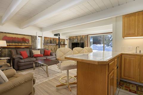 Open layout featuring living room with sofa, chairs, and kitchen island bar seating.