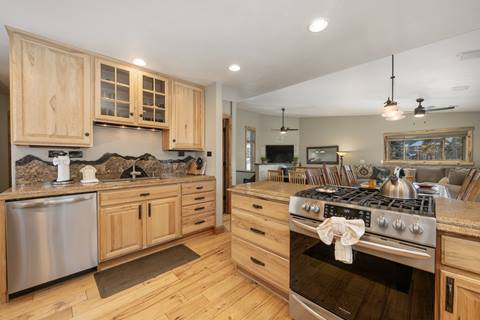  view of full home kitchen with oven, sink, refrigerator, and dishwasher, plus wooden furnishings. 