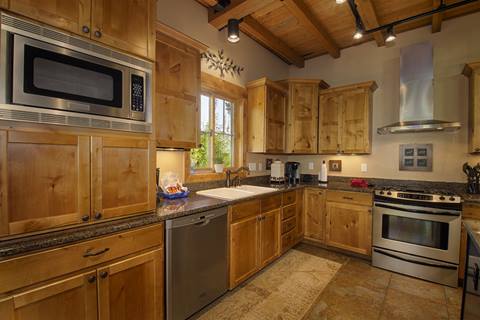 Full kitchen with wood cabinets and floor. Stainless steel oven. 