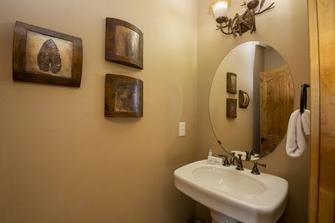 Small bathroom with tan walls and a sink below a mirror. 