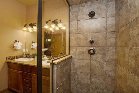 Tiled shower and warmly lit sink in the background. 