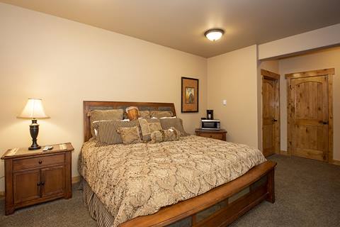 King bedroom with king bed and beige coverings. 