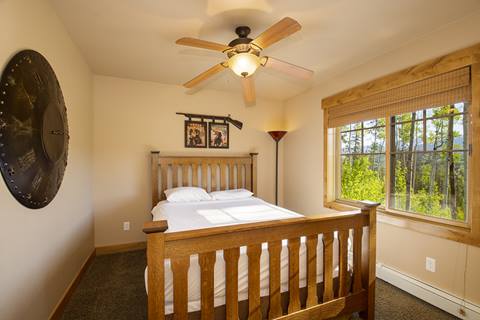 Double bedroom with white walls and a window looking out on aspen forest. 