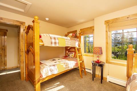 wooden frams bunk bed with in room with two windows. 