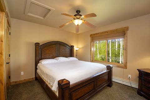 Queen bedroom with a ceiling fan, and a queen bed with white bedding. 